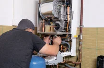 J&G Heating & Air Conditioning technician servicing a residential boiler